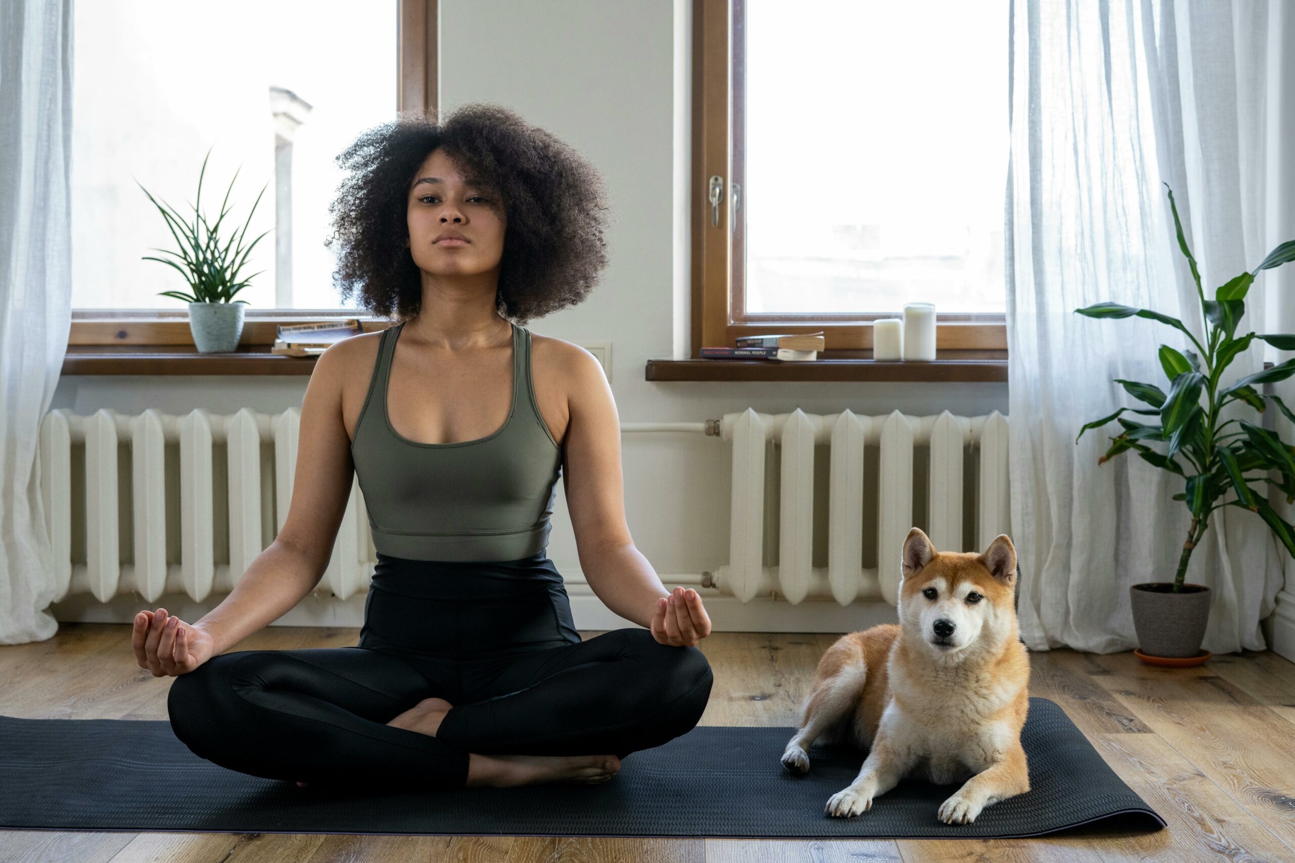 Woman meditating at home on a yoga mat with her dog