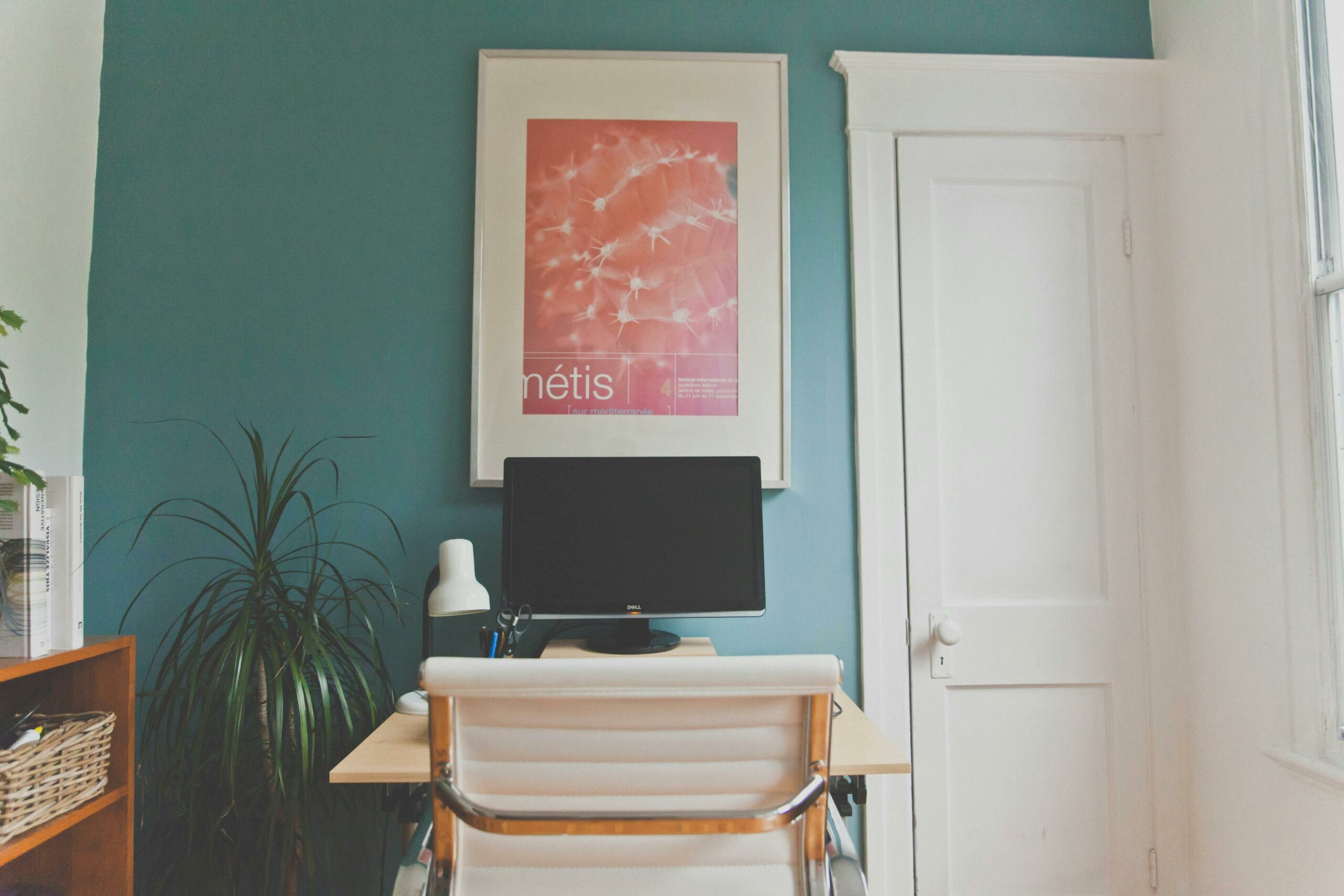 Home Office desk and computer with blue wall and framed poster.